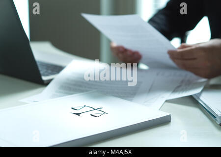 Uomo in possesso di un documento legale in mano. Avvocato in possesso di carta di legge in ufficio. Scala e simbolo di giustizia. Foto Stock