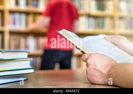 La gente in biblioteca pubblica o della scuola in un college o università. La lettura e la ricerca. Istruzione, studiando e letteratura il concetto di servizio. Foto Stock