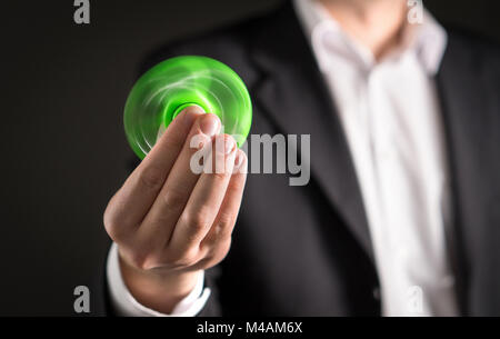 Uomo d'affari con un agitano: spinner. Imprenditore in un vestito tenendo trendy kids ansia sollievo giocattolo in mano. Foto Stock