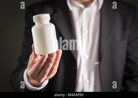 Rappresentante farmaceutica, consulente o testa direttore o manager della società di medicina con il flacone di farmaco. Uomo in una tuta azienda pillole o compresse Foto Stock