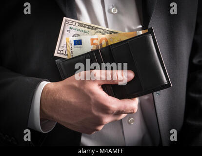 Dollari ed Euro nel portafoglio. Tasso di cambio, economia mondiale e concetto finanziario. Business man in un abito con la carta moneta, la banconota e bill in mano. Foto Stock