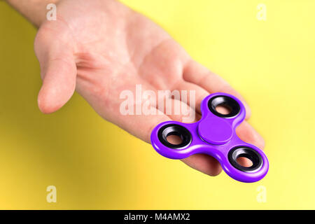 Viola e violetta agitano: spinner sul lato palmo e le dita contro sfondo giallo. Foto Stock