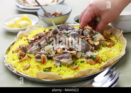 Mansaf è un tradizionale piatto arabo fatto di agnello cotto in una salsa di fermentati yogurt essiccata e servito con riso. Foto Stock