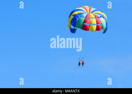 Turisti che si godono il parasailing isola in un cielo blu di Roatan, Honduras. Foto Stock