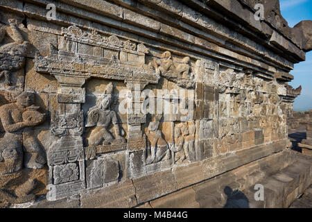 Rilievi su una parete del corridoio. Tempio Buddhista di Borobudur e a Magelang Regency, Java, Indonesia. Foto Stock