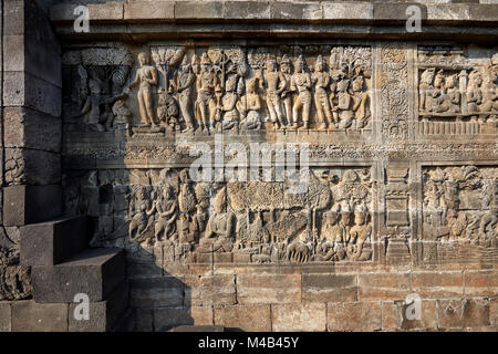 Rilievi su una parete del corridoio. Tempio Buddhista di Borobudur e a Magelang Regency, Java, Indonesia. Foto Stock