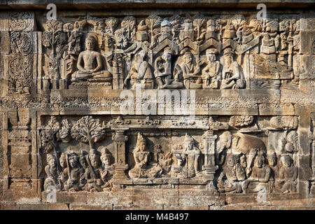 Rilievi su una parete del corridoio. Tempio Buddhista di Borobudur e a Magelang Regency, Java, Indonesia. Foto Stock