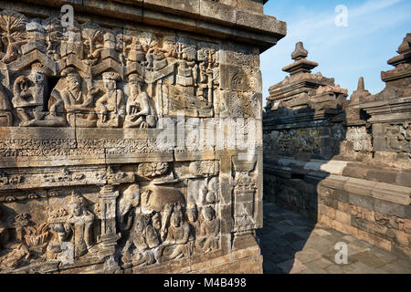 Rilievi su una parete del corridoio. Tempio Buddhista di Borobudur e a Magelang Regency, Java, Indonesia. Foto Stock