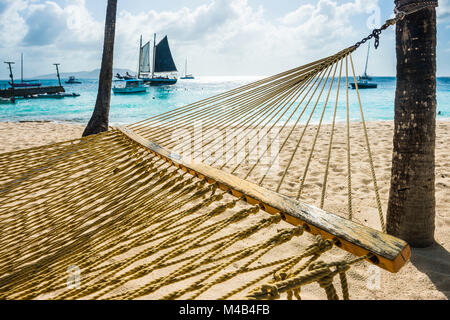 Amaca tra due palme su di una spiaggia di sabbia,Palm Island,Grenadine Isole,San Vincent e Grenadine,dei Caraibi Foto Stock