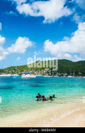 Bambini locali nelle acque turchesi del Admirality bay,Bequia,San Vincent e Grenadine,Carribean Foto Stock