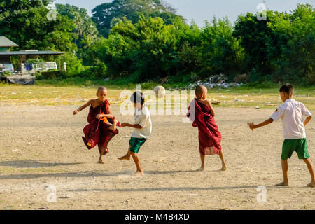 Giovani monaci sono giocare a calcio con i ragazzi locali Foto Stock