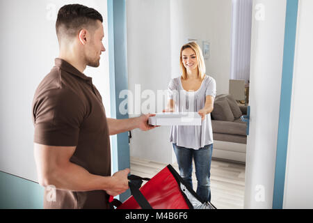 Gentile Uomo di consegna Consegna Pizza a Felice Giovane Donna Foto Stock