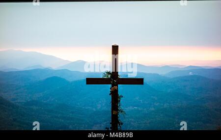 Il culto cristiano croce che affaccia sulle montagne di sunrise Foto Stock