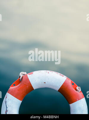 Grungy salvagente contro acqua oceanica Foto Stock