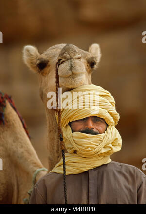 Algeria, Djanet. Uomo di tribù Tuareg e cammello. Deserto del Sahara. Ritratto. Foto Stock