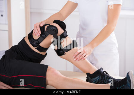 Close-up di una femmina di fisioterapista dando gamba esercizio in clinica Foto Stock