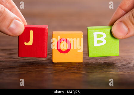 Persona Lato disporre blocchi per rendere la parola lavoro sulla tabella Foto Stock