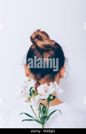 L'immagine verticale di fiore bianco con gambo lungo e la ragazza con i capelli bruni close-up Foto Stock