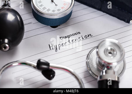 Close-up di testo ipertensione diagnosi;lo stetoscopio e la pressione sanguigna Calibro sulla forma medica Foto Stock