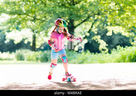 Equitazione per bambini skateboard in estate park. Bambina di imparare a cavalcare skateboard. Active outdoor sport per la scuola e per la scuola materna i bambini. Bambini skat Foto Stock