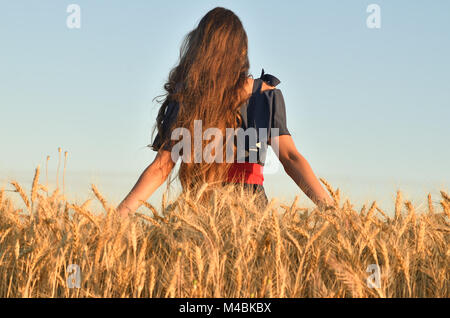 La ragazza si erge nel mezzo del campo e tocca le orecchie Foto Stock