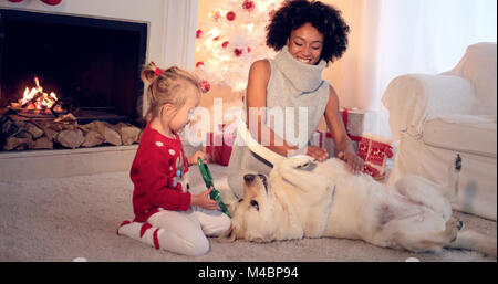 Mamma e figlia in maglioni giocare con il cane Foto Stock