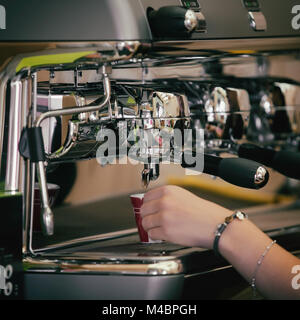 Barista prepara il caffè nella sua caffetteria; close-up Foto Stock