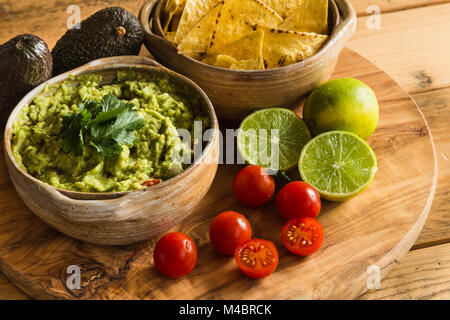 Guacamole dip in ciotola con tortilla chips e ingredienti Foto Stock