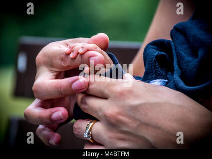 Baby messicana con le sue dita sul dito di madri Foto Stock