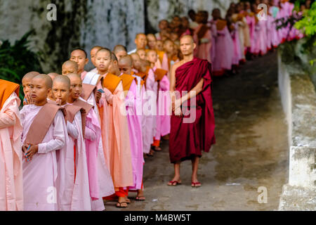 Le monache buddiste sono in coda in una lunga fila per ricevere donazioni in un monastero Foto Stock