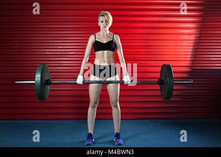 Donna muscolare in una palestra facendo pesanti esercizi di peso Foto Stock