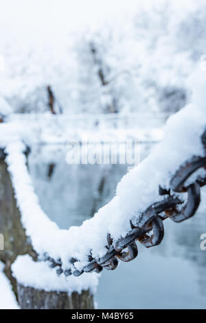 Vecchio arrugginito catena di ferro su un gelo con neve Foto Stock