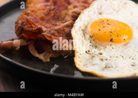 Uovo fritto e fette di bacon Foto Stock
