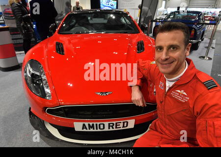 RAF frecce rosse squadron leader Adam Collins con una Aston Martin rosso 10, che è stato venduto all'asta di beneficenza in anteprima per il London Classic Car Show, in ExCeL nella zona est di Londra. Foto Stock