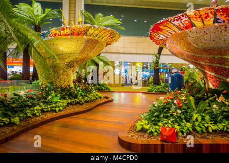 SINGAPORE - circa agosto, 2016: vista interna delle persone che camminano in un piccolo giardino con piante all'interno dell'Aeroporto Changi di Singapore. L'Aeroporto Changi di Singapore è il principale aeroporto civile per Singapore Foto Stock