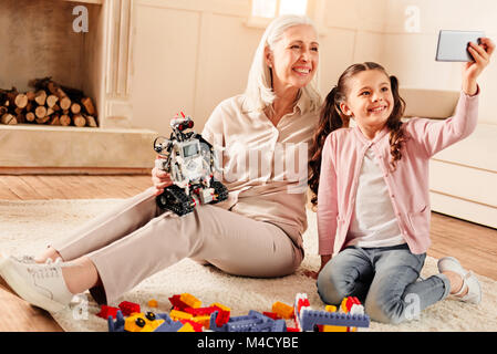 Smart bambina tenendo selfie con nonna radiante Foto Stock