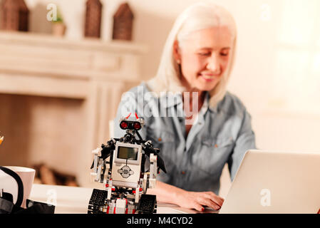 Robot impressionante in piedi sulla tavola della signora anziana Foto Stock