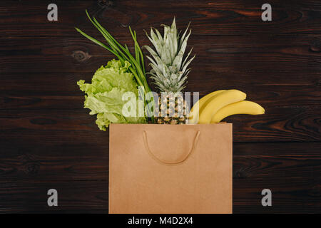 Vista superiore del cavolo cinese, ananas e banane in borsa per la spesa sul tavolo di legno Foto Stock