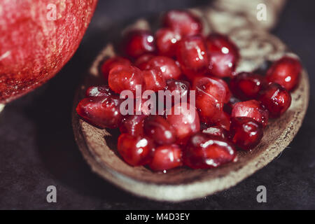 Chicchi di melograno con cucchiaio rustico Foto Stock