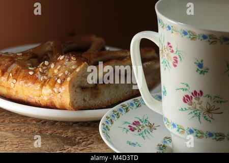 Bella tazza dipinta con fiori e un pezzo di dolce Foto Stock