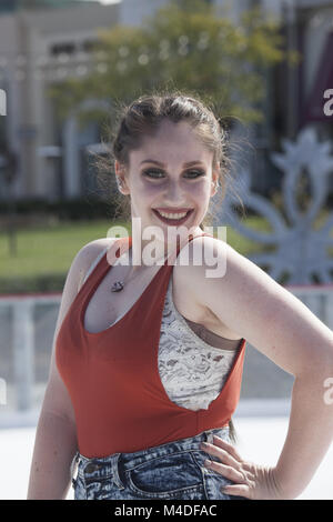 Sorridente giovane donna con atteggiamento impertinente in un serbatoio superiore all'aperto Foto Stock