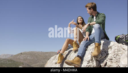 Due giovani turisti che si siedono su roccia Foto Stock