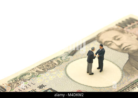 Miniaturizzati a 2 persone imprenditori agitare le mani Stand sulle banconote giapponese vale la pena 10.000 yen usando come sfondo il concetto di business e finanza concetto con Foto Stock