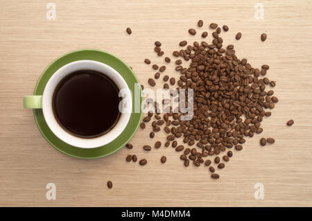 Green tazza di caffè sullo sfondo del legno di rosa tableand sparsi i chicchi di caffè. Vista dalla parte superiore Foto Stock