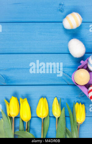 Bouquet fresco di tulipani gialli e uova di Pasqua avvolto stringa di lana su schede di blu, copiare lo spazio per testo o iscrizione Foto Stock