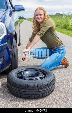 Ragazza olandese cambiare auto ruota sulla strada di campagna Foto Stock