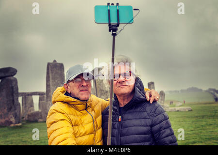 Uomini maturi amici prendere un selfie in Stonehenge il sito archeologico - Concetto di active senior che viaggiare e divertirsi Foto Stock