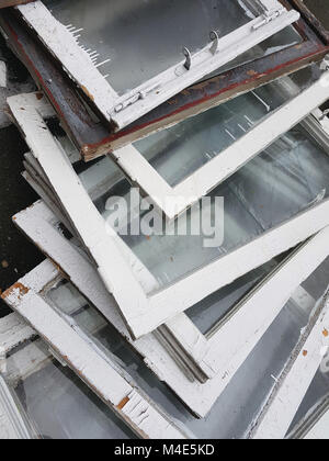 Dump, garbage: i vecchi infissi in legno di colore bianco con nuvoloso riquadri grigi, impilati nell'heap, cambiamento di windows, telaio verticale. Foto Stock