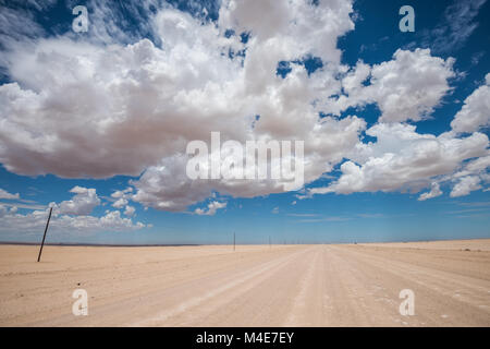 Immagine vibrante della strada nel deserto e blu cielo nuvoloso Foto Stock