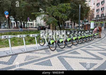 Lisbona, Portogallo: Noleggio di biciclette elettriche parcheggiate in città. Una coppia che prova una bicicletta Foto Stock